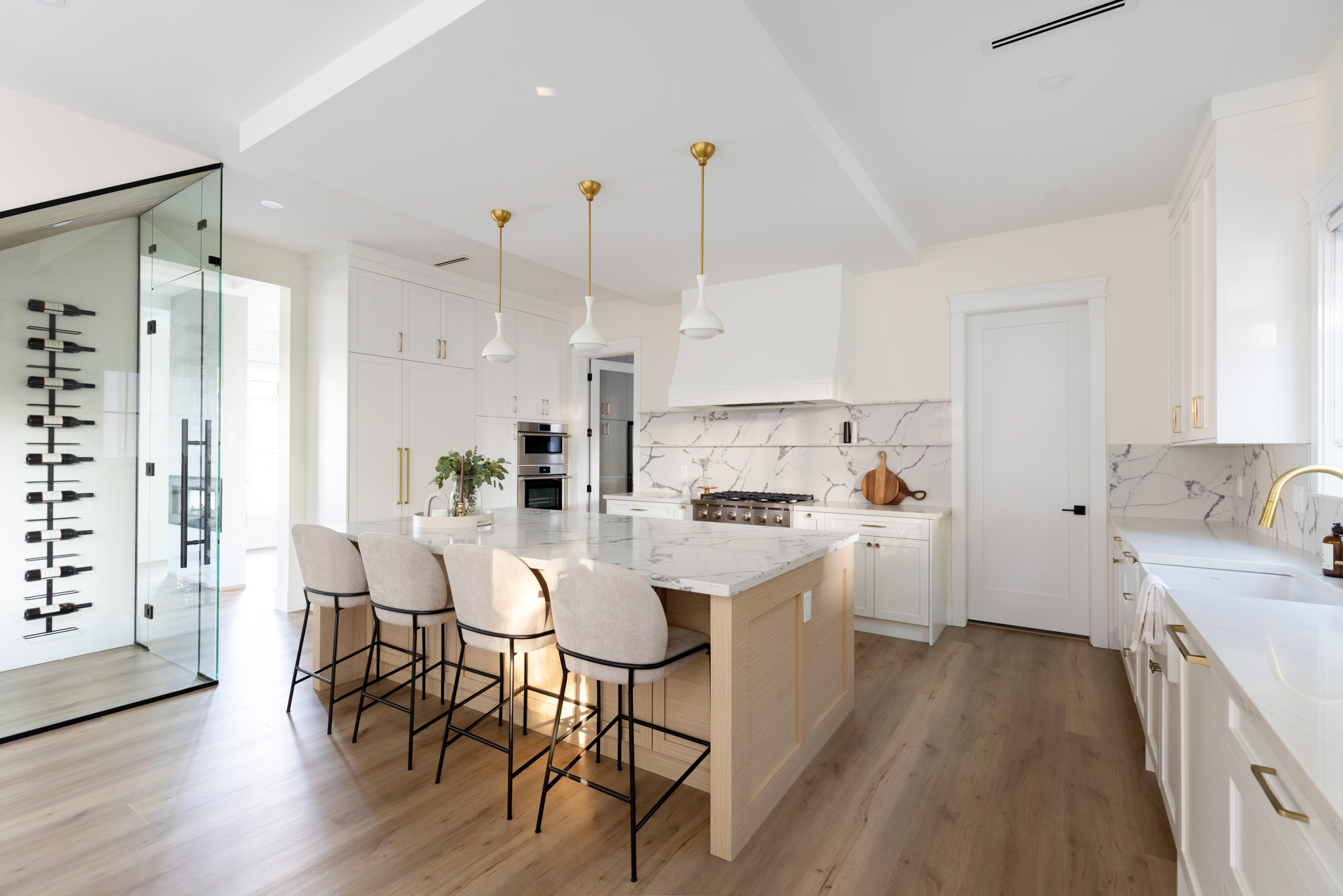 Signature Service project — open-concept kitchen with white oak island, marble countertops, and glass wine cellar